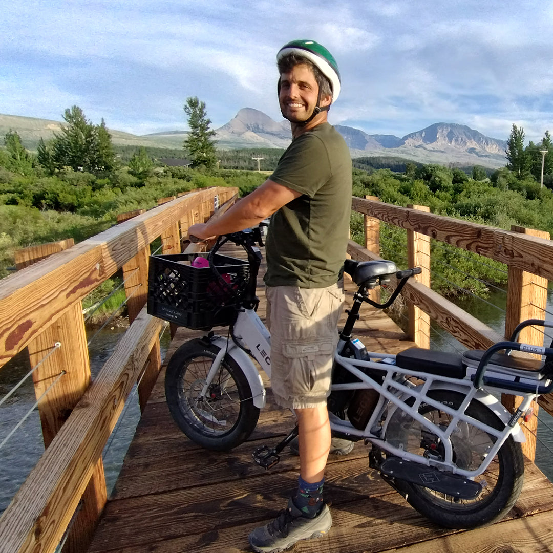 Man in shorts on Xpedition Cargo bike on a bridge in Glacier National Park.