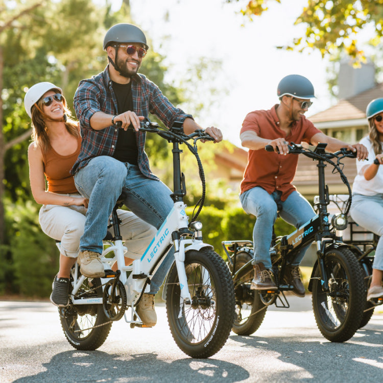 a man is riding a Lectric XP Step-Thru 3.0 outside in a group with a woman on the rear rack