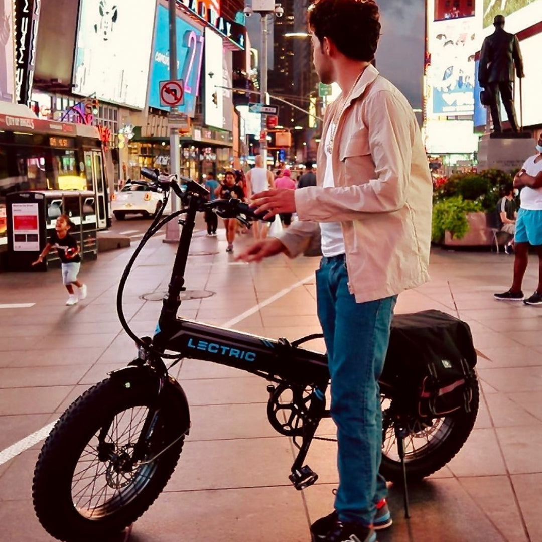 man standing next to his Lectric ebike in a busy city