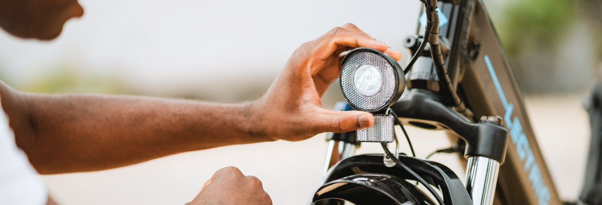 Man adjusting premium headlight on a black Lectric XPremium bike