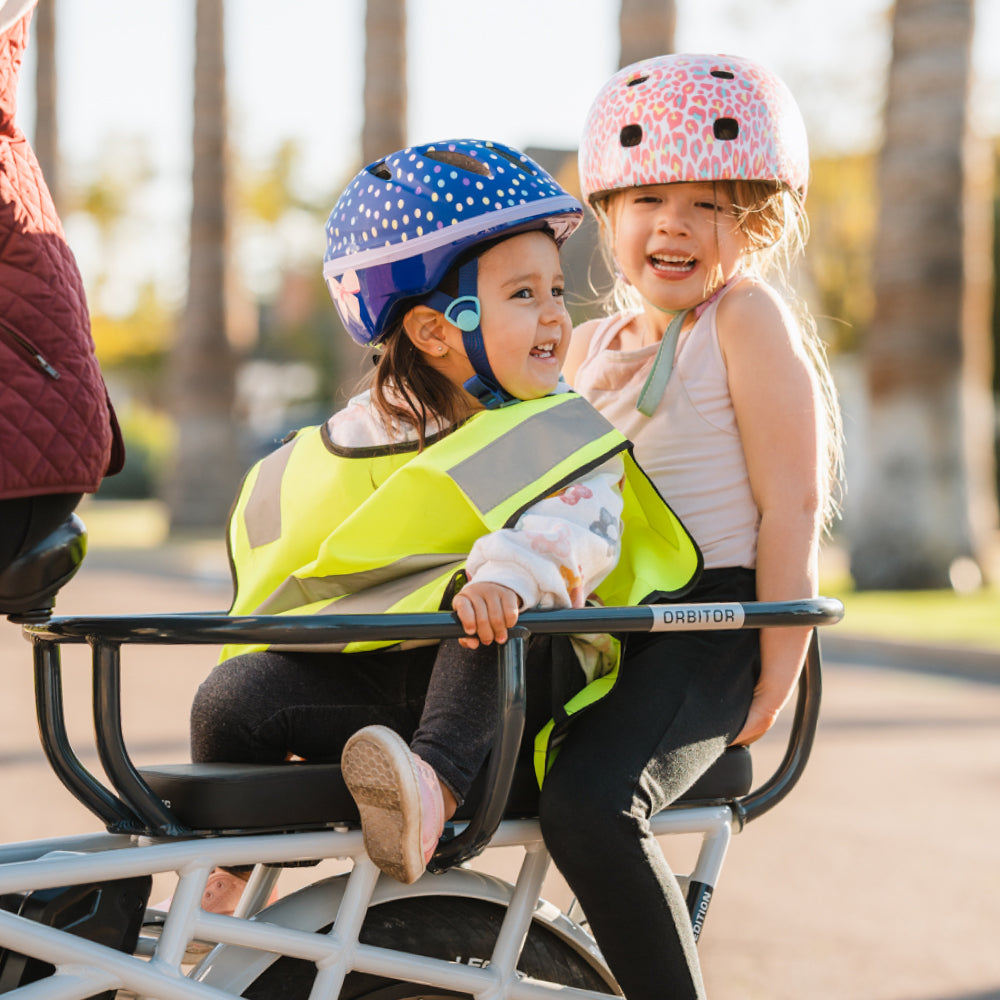 Children in bike helmets riding in orbitor on cushions on the back of Lectric XPedition