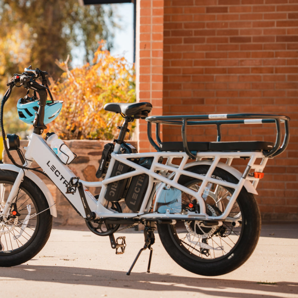 Parked Lectric dual-battery XPedition with cushions and orbitor and blue bike helmet on handlebars