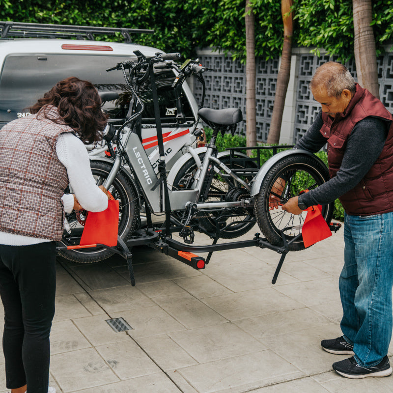couple mounting a Lectric eBikes XP Trike to Hollywood Rack on the back of their SUV
