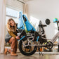 Woman attaching two Yepp seats to the back of the XPedition cargo ebike with bike helmets on the wall