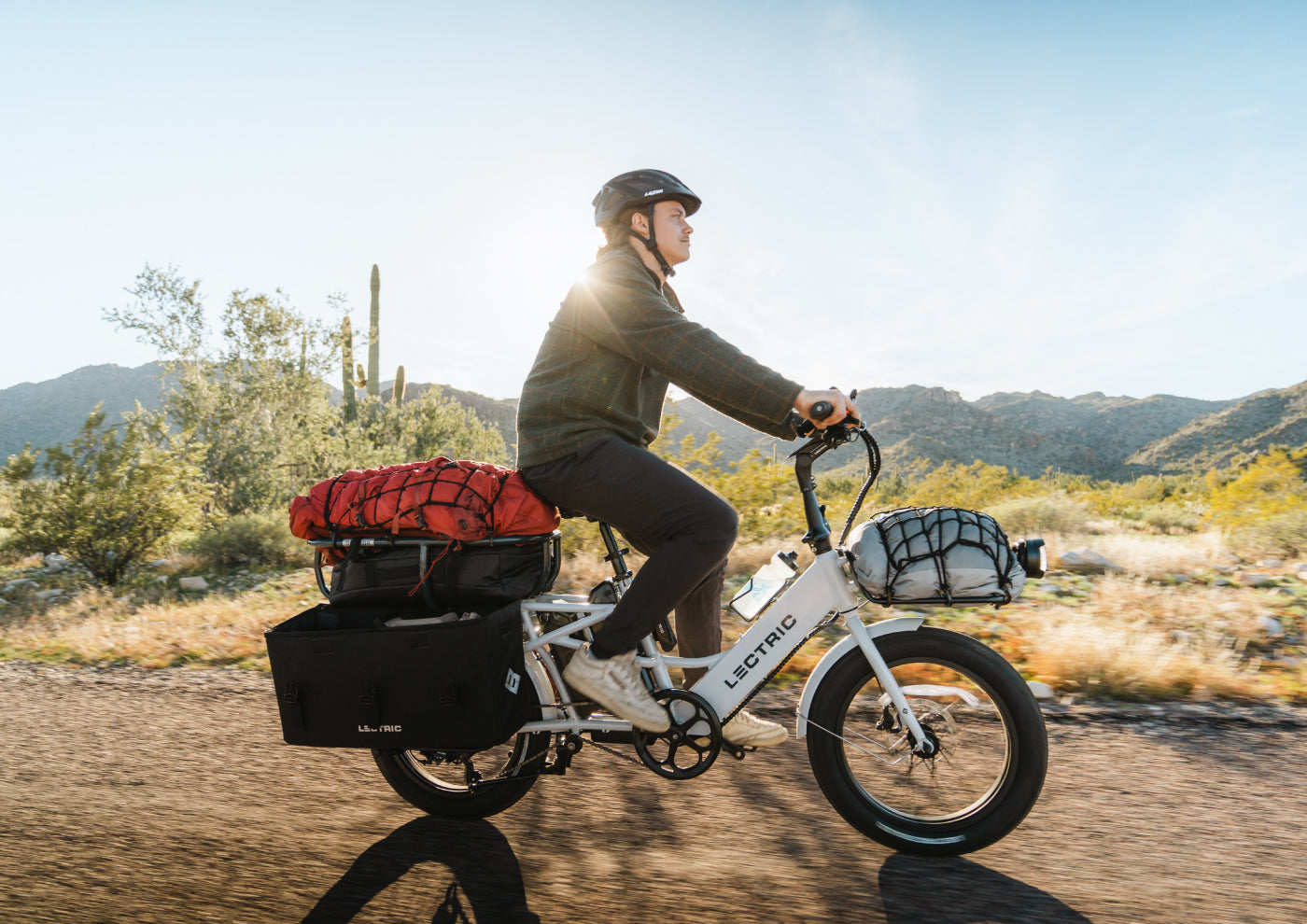 Man riding on XPedition cargo bike in the desert carrying supplies on racks, orbitor, and XL cargo panniers