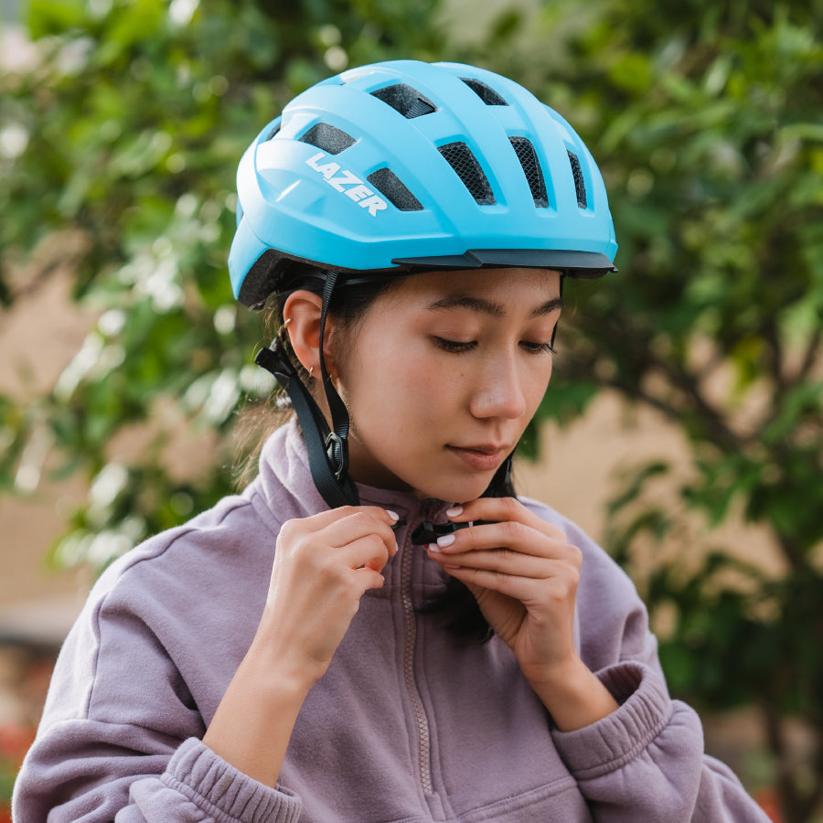 young woman clipping her blue lazer helmet