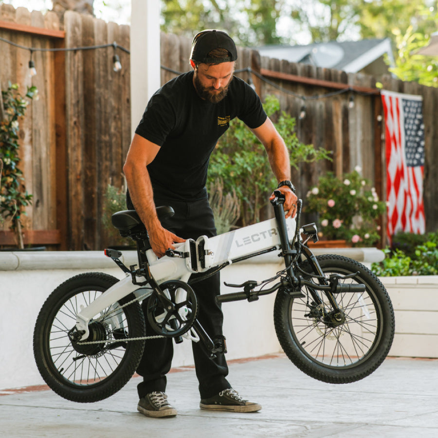 Man folding 1.0 Arctic XP Lite while handlebars are folded with American flag on back