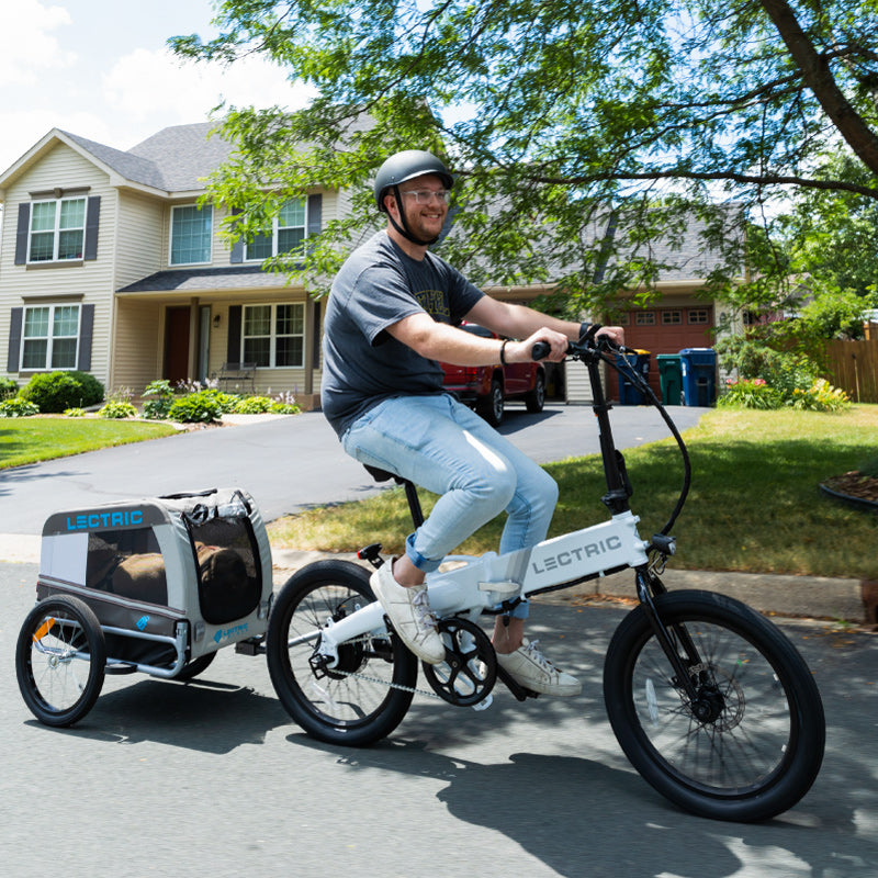 man riding ebike with wag-along pet trailer on scenic neighborhood road