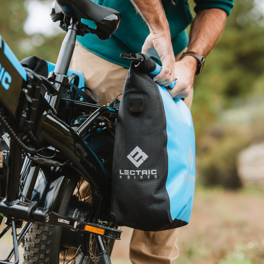 Close up of a waterproof pannier bag installed on the rear rack of an electric bike in the woods