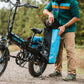 Man in the woods putting a hat into a blue waterproof pannier bag installed on rear rack of ebike
