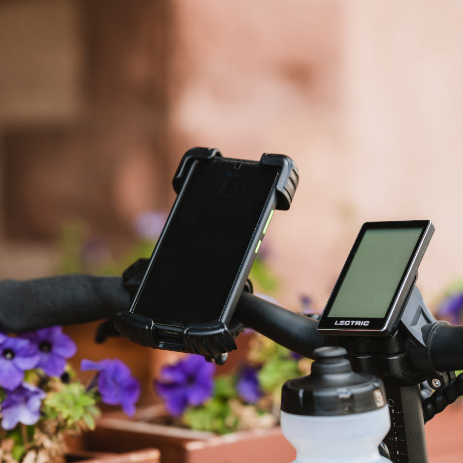 black phone mount on the handlebars on a class 3 ebike with a phone in it next to an lcd display and water bottle